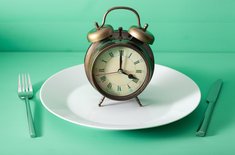 fork and knife crossed and alarm clock on plate