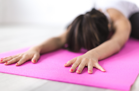woman in childs pose on yoga mat