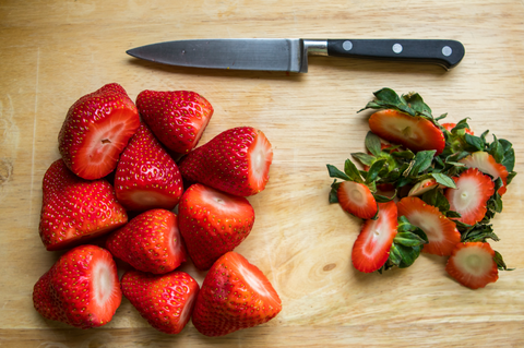 Freshly chopped strawberries on a chopping board with a knife