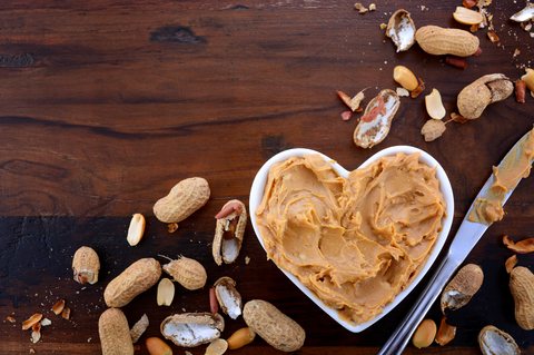 peanut butter and shelled peanuts in bowl on wooden surface