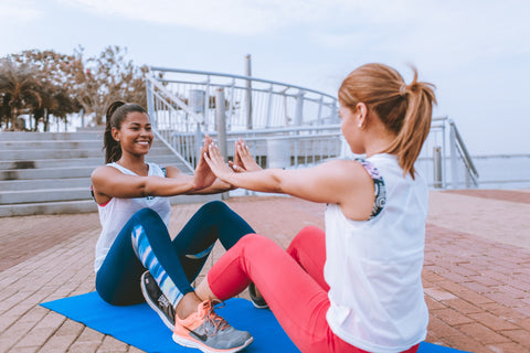 Two women exercising outside on yoga mats