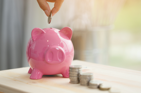 Little hand saving money in pink piggy bank