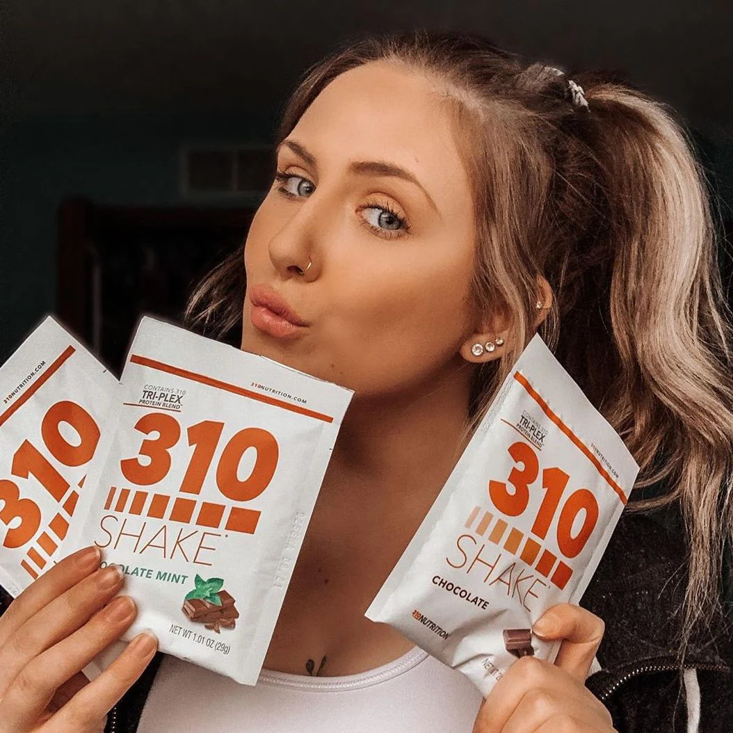 Person holding 310 Shake packets, promoting dietary supplements.