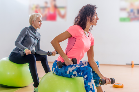 Sporty slim women taking part in gym fitness class exercising