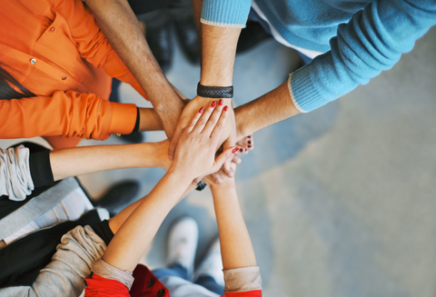 Top view image of group of young people putting their hands together