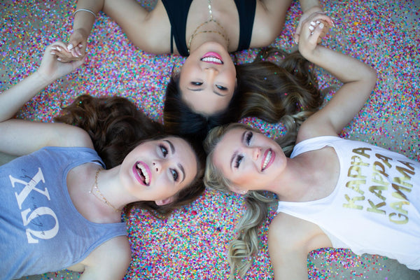 Sorority themed photoshoot of three girls lying down with heads touching