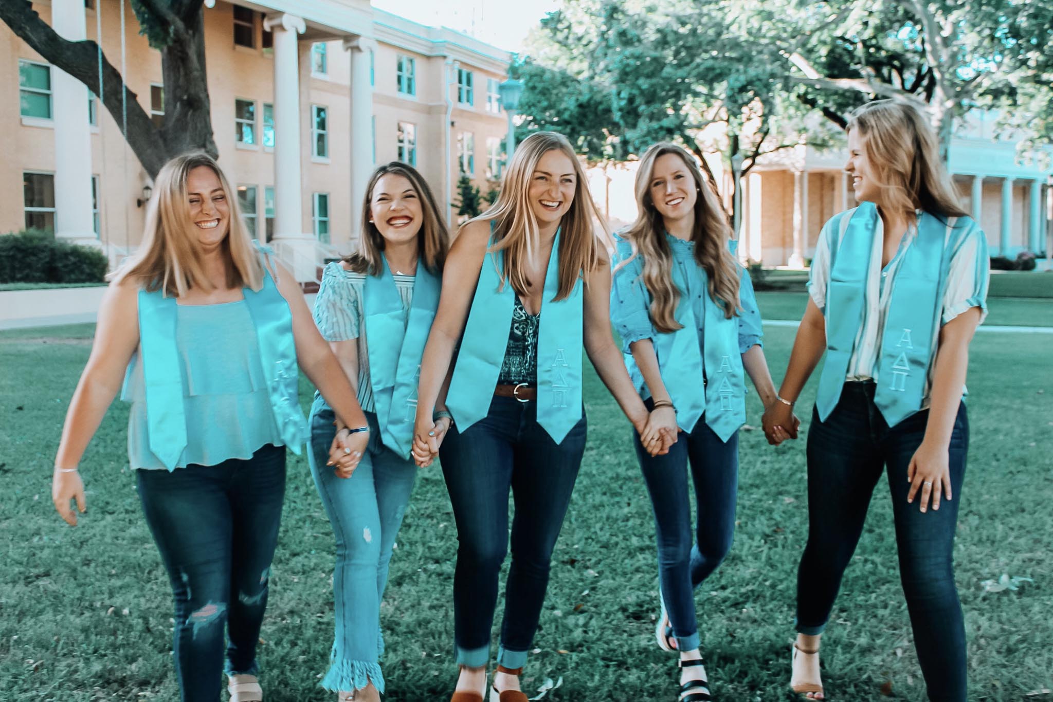 Sorority sisters walking together on campus with turquoise tinted clothing and background