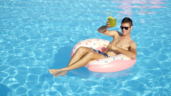 Man Floating In A Raft With A Pineapple Drink