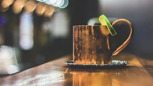 copper mug with citrus slice wedged on its rim placed on a silver coaster