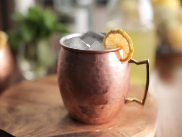 Moscow Muled copper mug filled with ice cubes and lemon slice wedged on its rim