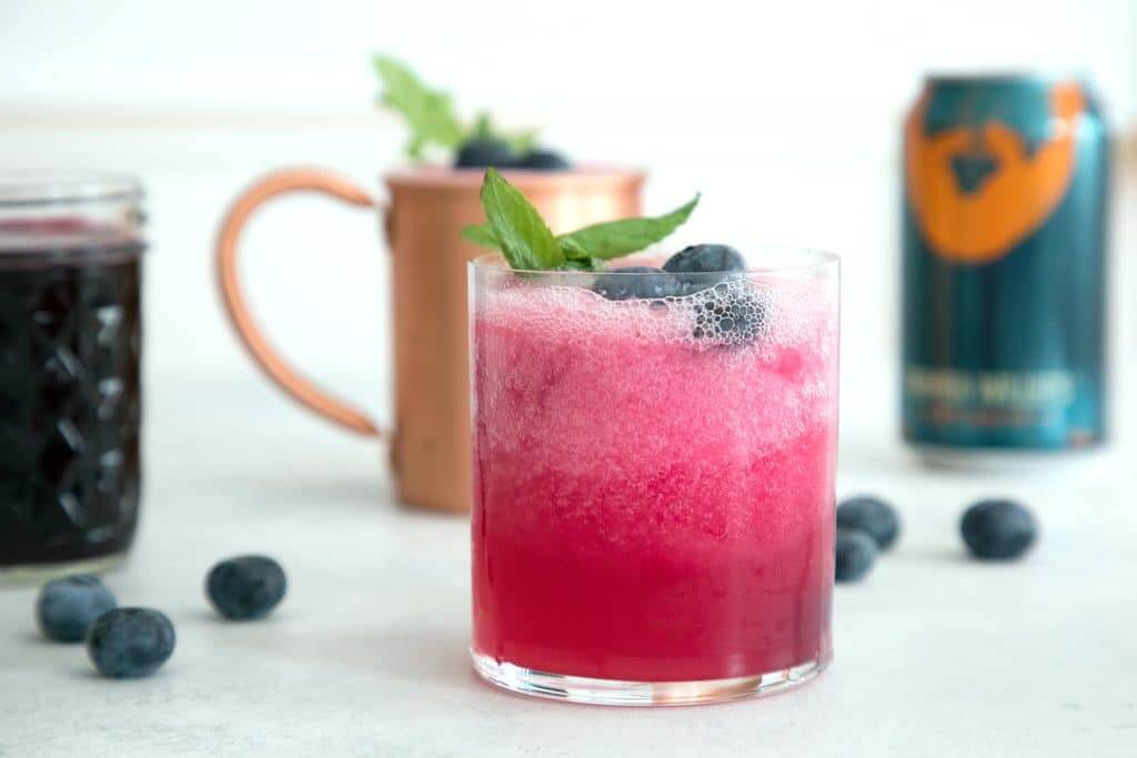 clear glass filled with pink liquid and copper cup in the background