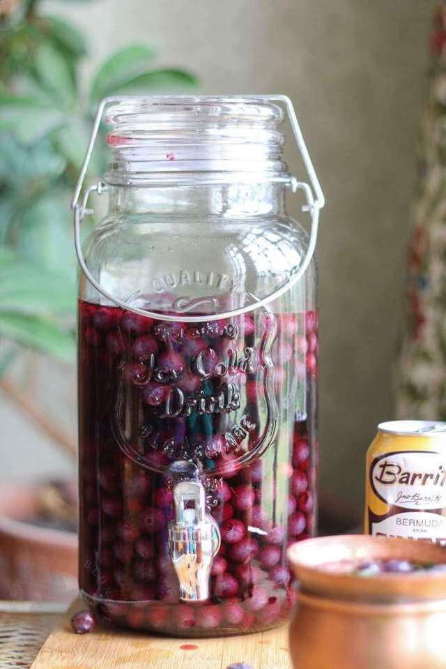 clear mason jug containing with dark pink liquid and blueberries