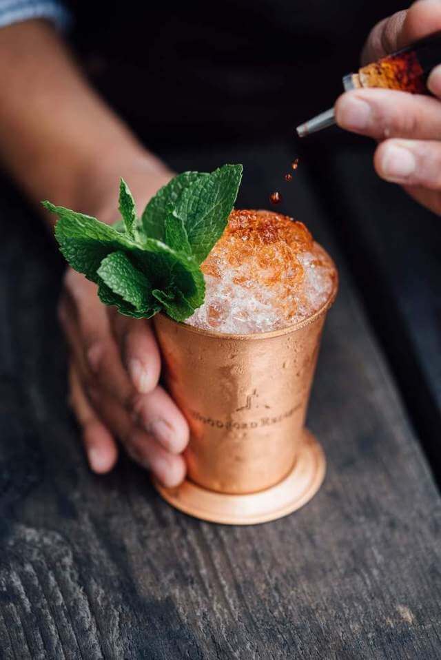 hand holding copper cup filled with crushed ice and mint leaves