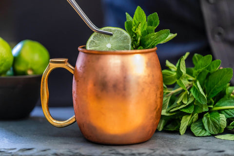 side view of copper mug with slice of lime and mint leaves