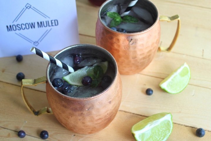 two Moscow Muled copper mugs filled with liquid lime slices and blueberries
