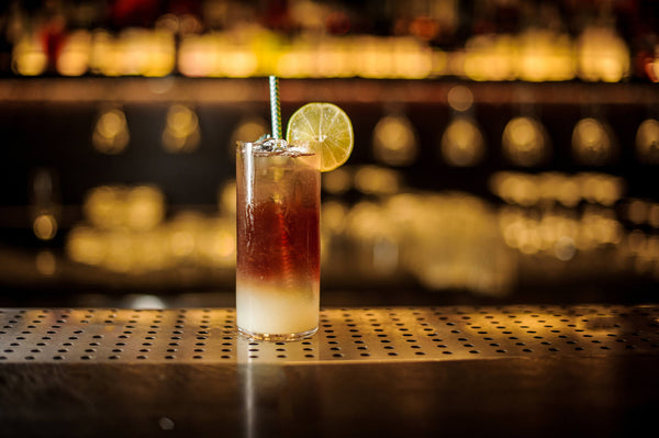 clear glass filled with gradient brown colors stainless steel straw ice and sliced citrus