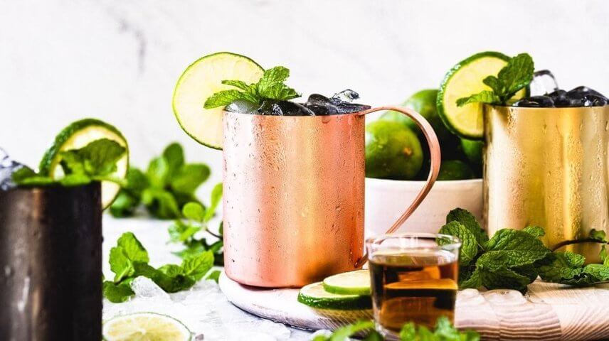 three copper mugs containing ice mint leaves and ice side view