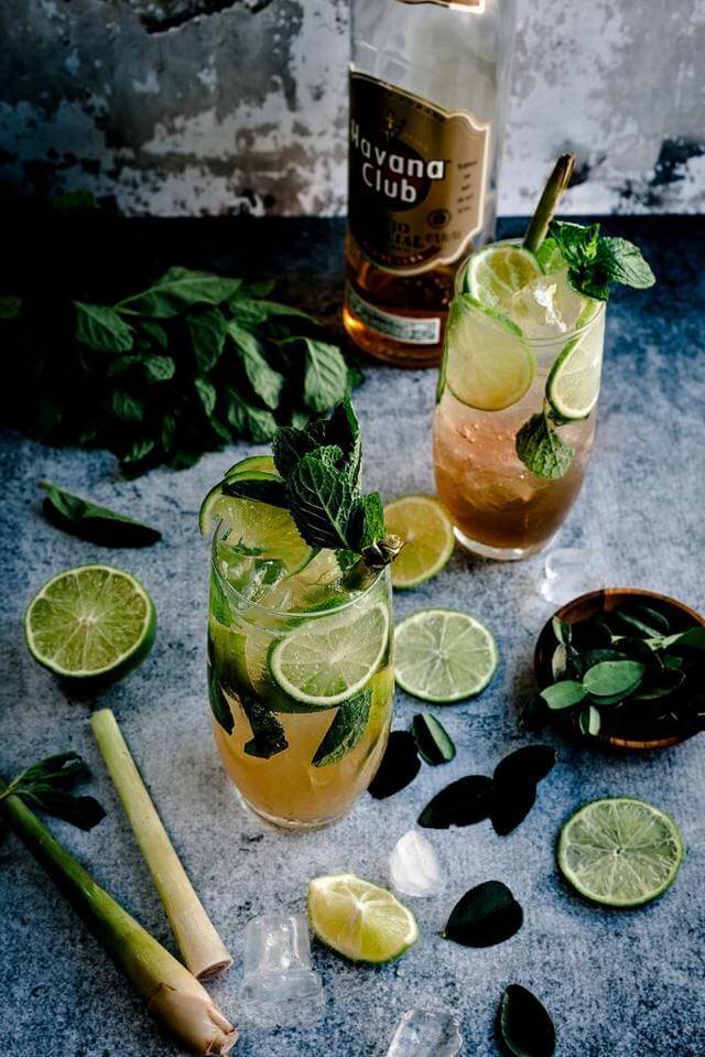 two clear glass filled with liquid mint leaves and citrus slices