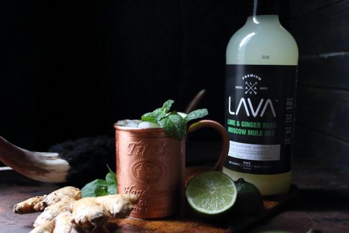 copper cup filled with crushed ice and mint leaves beside pieces of ginger and sliced lime