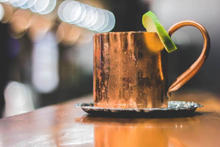 copper mug with a green citrus slice wedged on the rim placed on a silver coaster