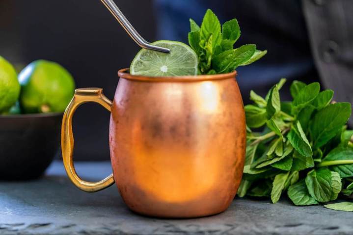 copper mug with lime slice being placed using stainless steel tool