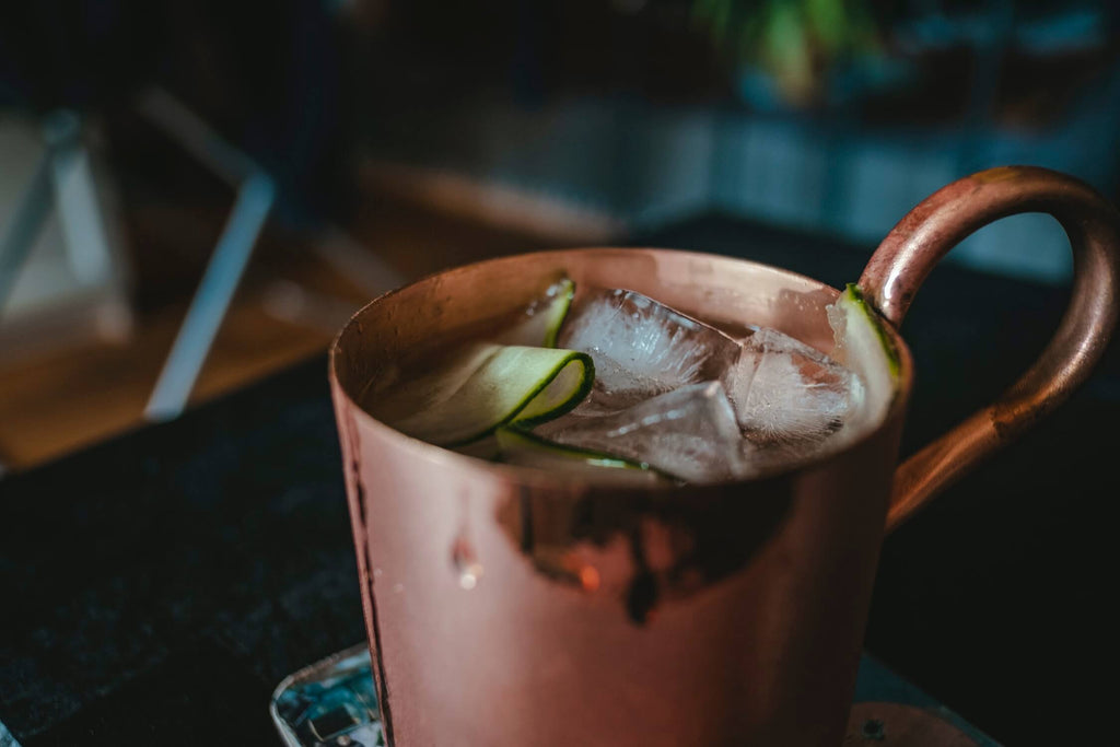 copper mug filled with liquid ice and cucumber strip