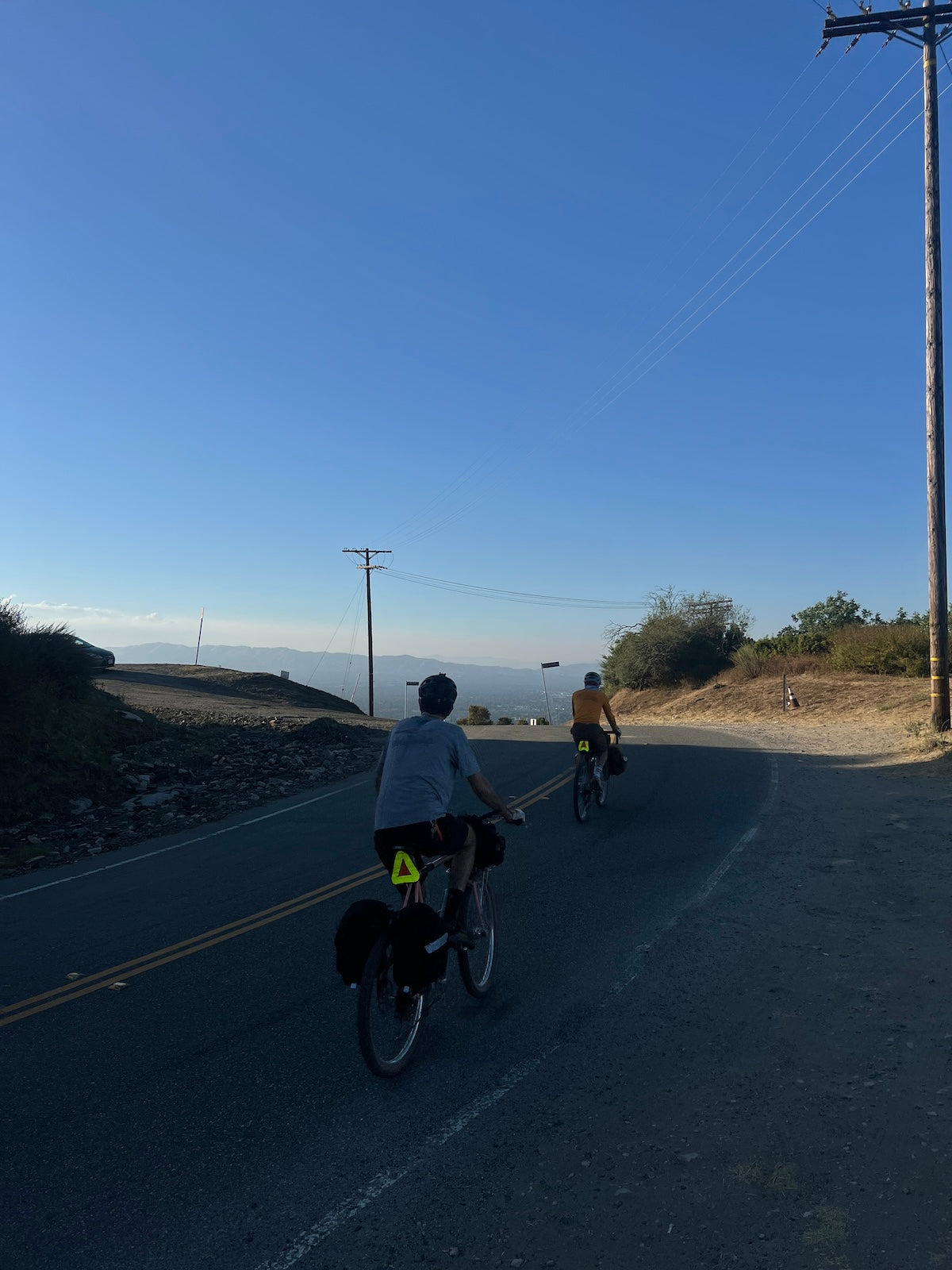 Two cyclists in a shaded part of Mulholland Drive before starting the gravel climb