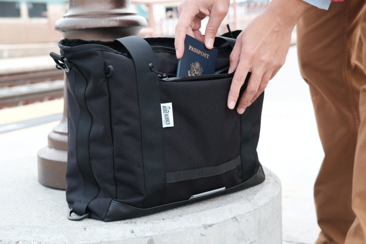 Passport being placed inside the front pocket of a Road Runner Bags Everything Tote Bag