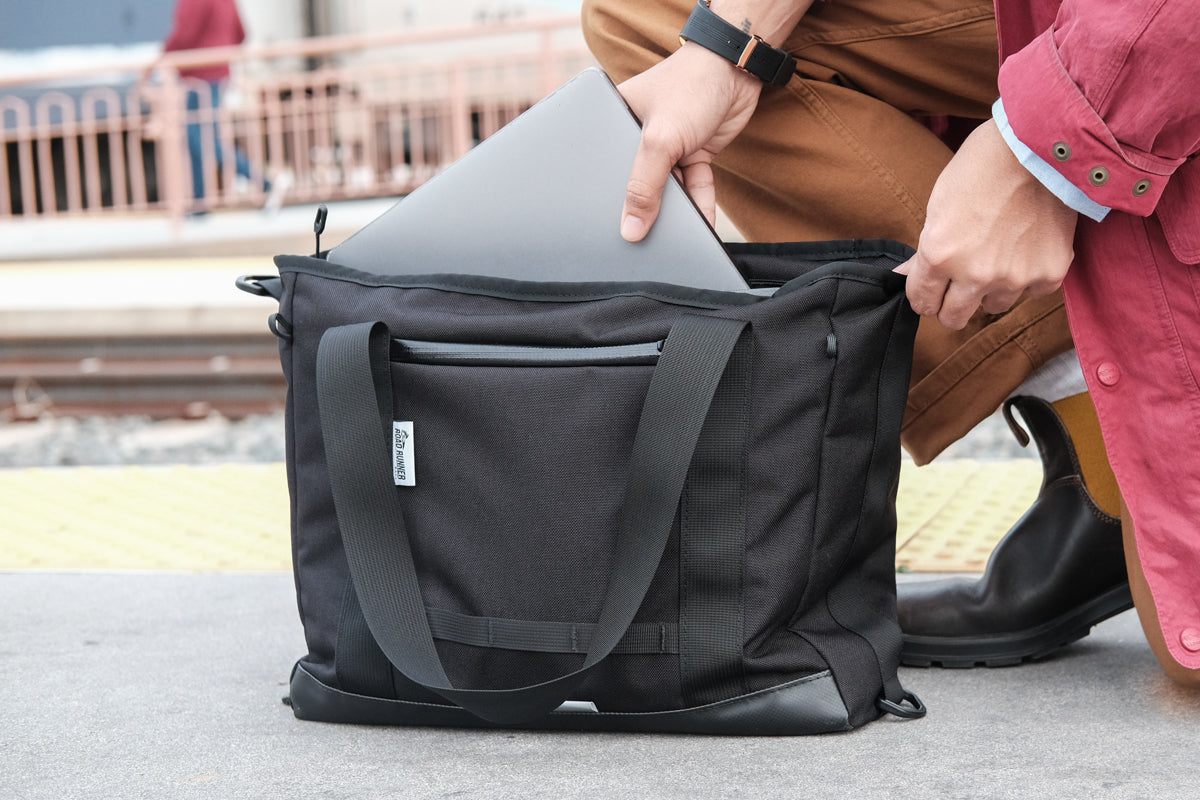 Laptop being pulled out of a Road Runner Bags Everything Tote Bag at train station