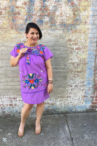 ShopMucho models women's Mexican dress in purple with embroidered flowers