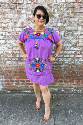 ShopMucho models women's Mexican dress in purple with embroidered flowers