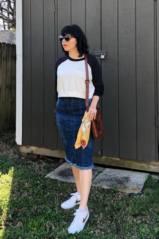 ShopMucho ower models Mucho merch, spice crop top, denim pencil skirt, nikes, leather purse, and Luchadora bandana.