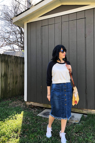 ShopMucho ower models Mucho merch, spice crop top, denim pencil skirt, nikes, leather purse, and Luchadora bandana.