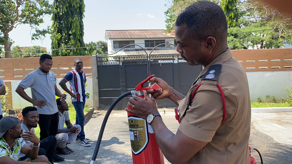 Firefighter teaching how to use fire extinguisher, part of Osei-Duro’s practical skills training for team empowerment.