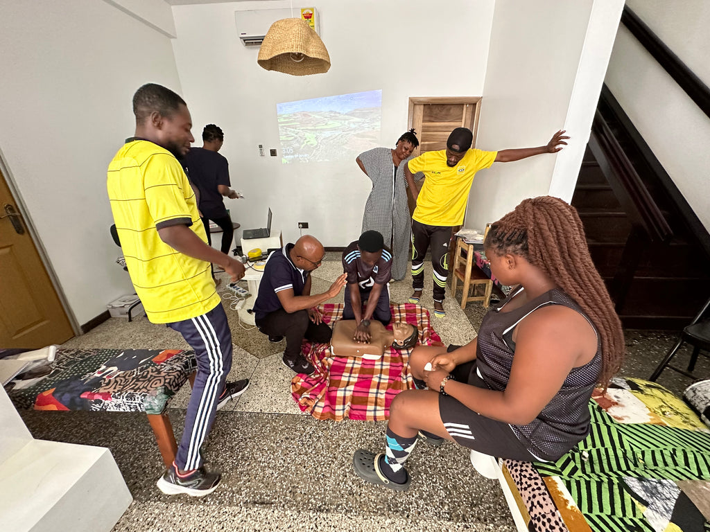Team learning CPR on the floor during Osei-Duro training workshop.