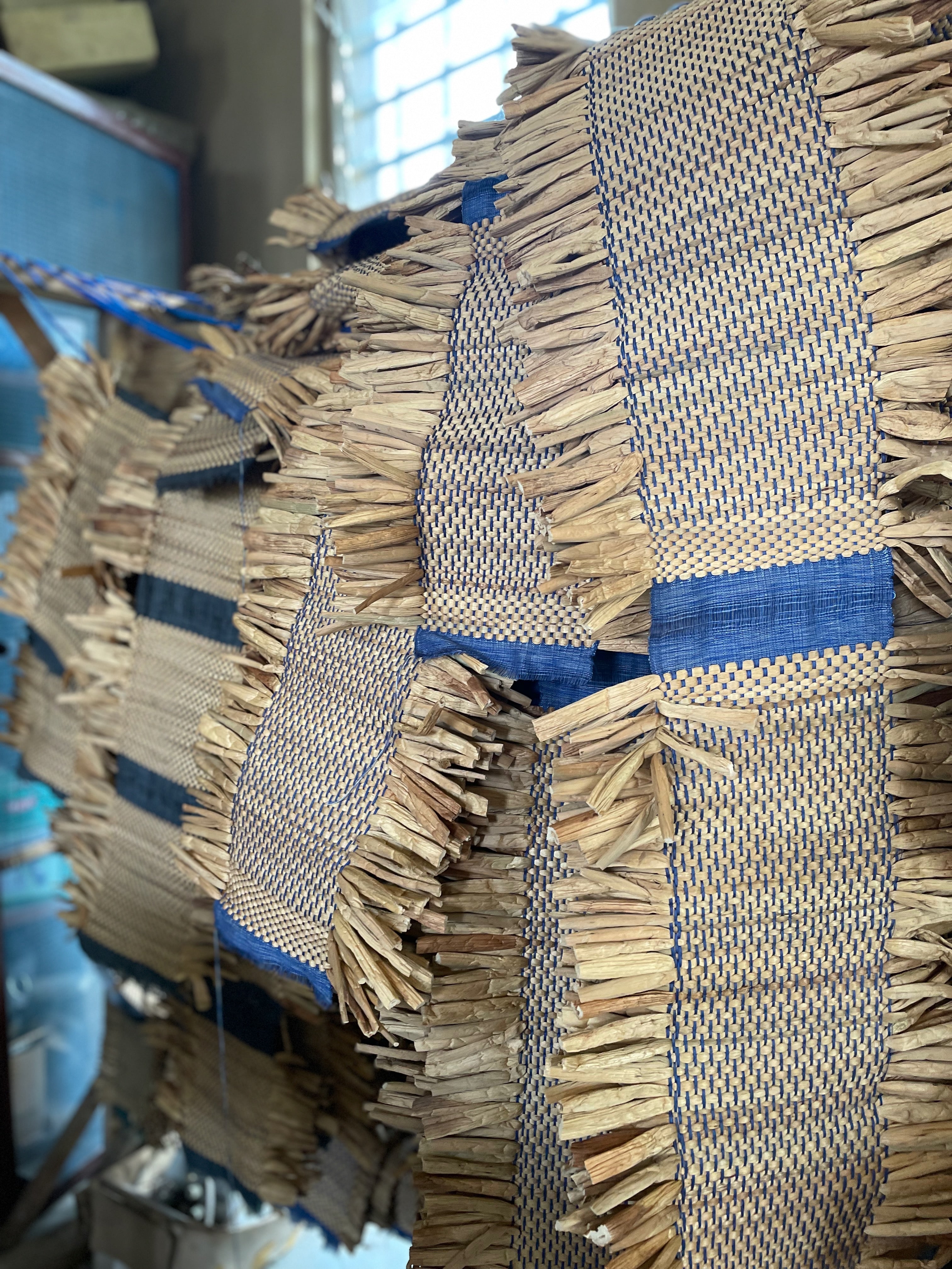 Close-up of straw mats woven with blue fibers.