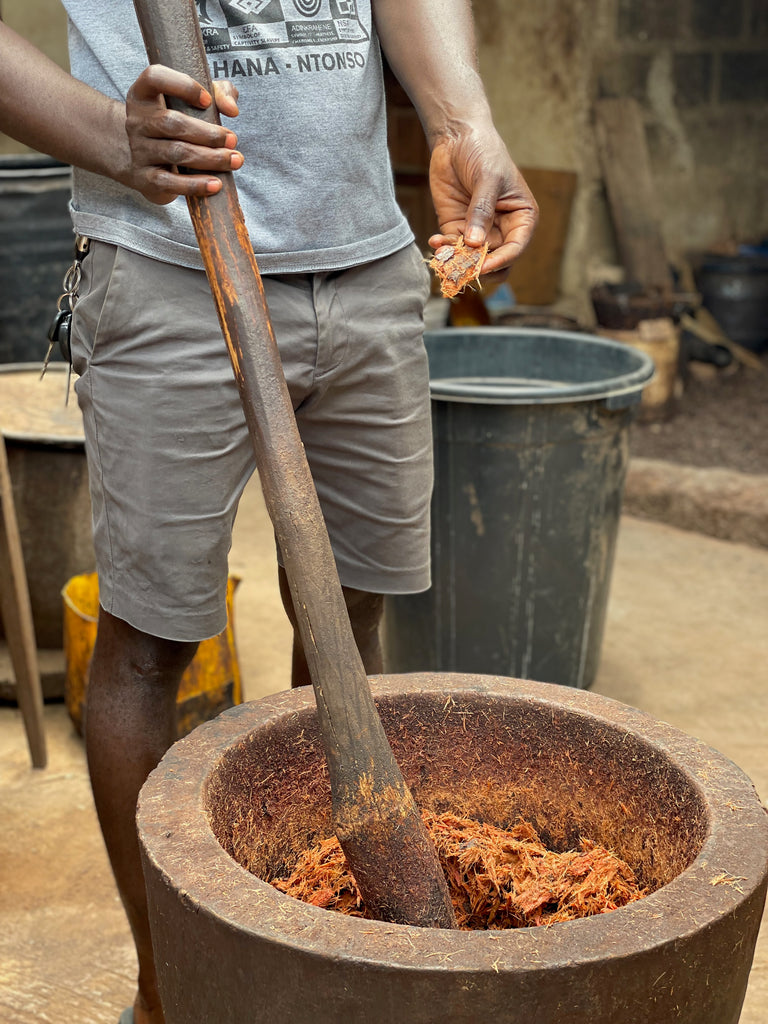 man is stirring a pot of plant matter used for dyeing fabric.