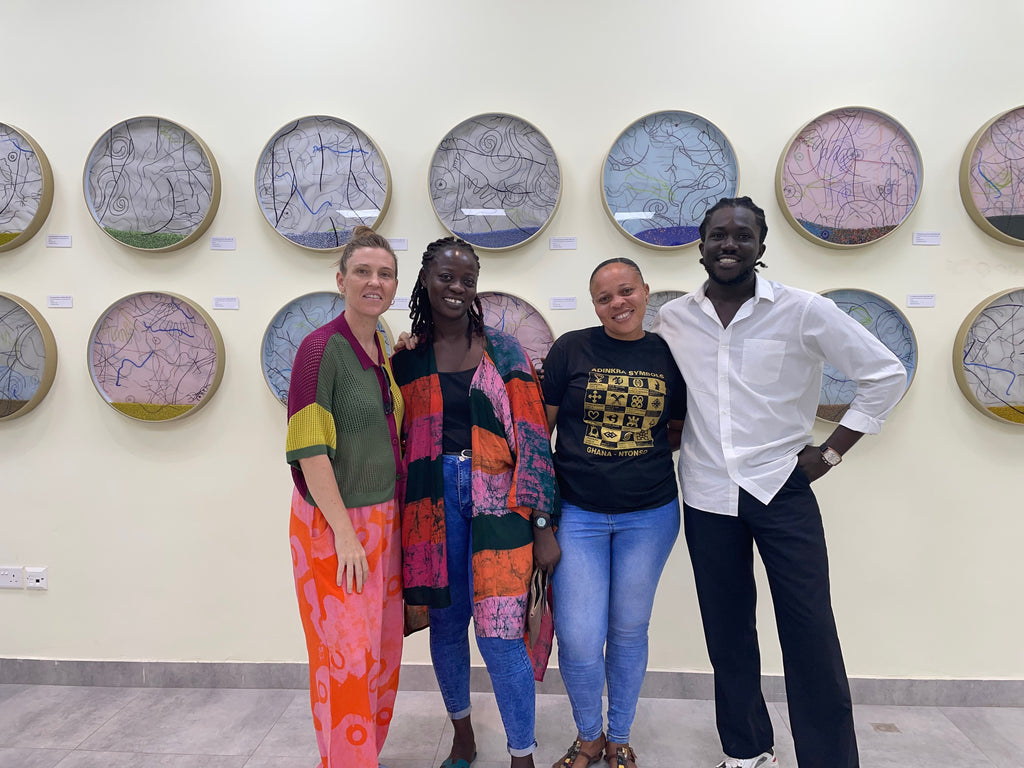 Art display of circular artworks with intricate designs, four people stand posing in front of artwork.