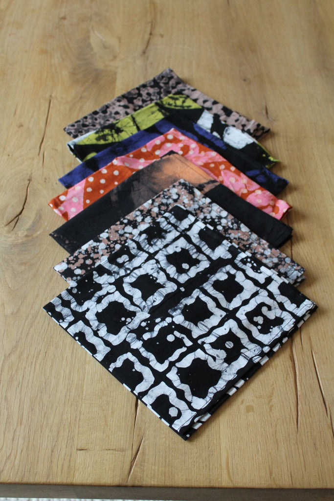 Assorted Osei-Duro batik print napkins arranged on a wooden table.