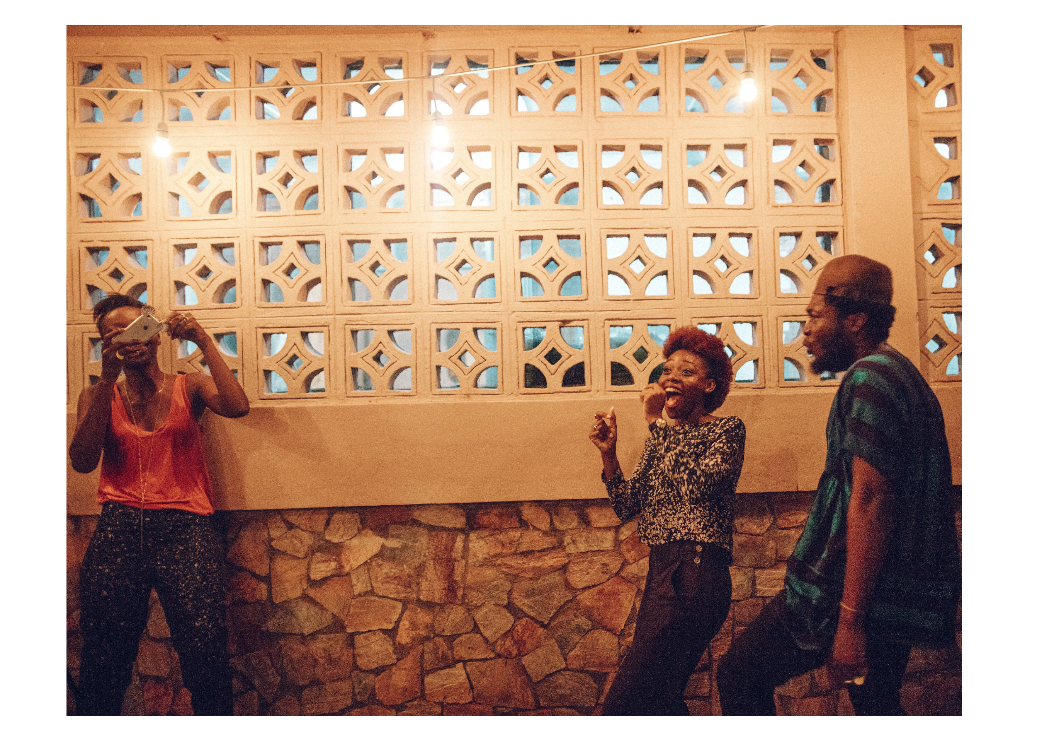 Three individuals standing in front of a wall with a decorative geometric pattern.