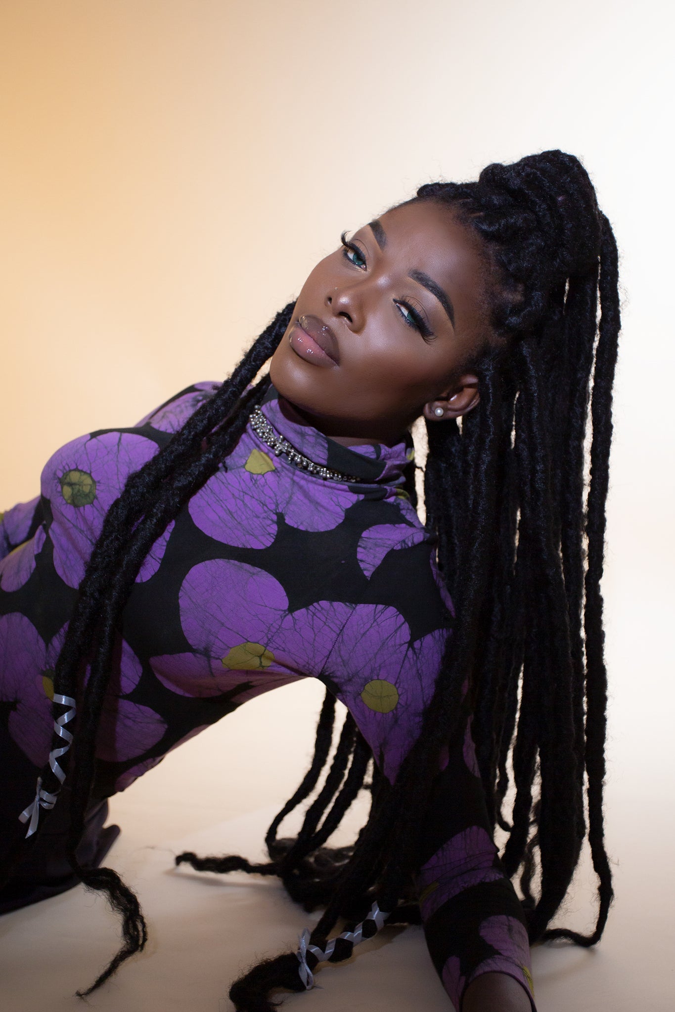Woman in Osei Duro’s purple floral Stricta Turtleneck, exudes an air of intrigue and style.