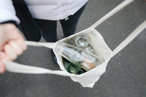 Woman holds a reusable bag filled with bottles for recycling