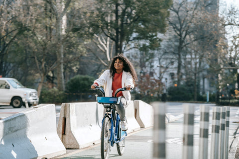 Happy woman riding a blue bike through the city