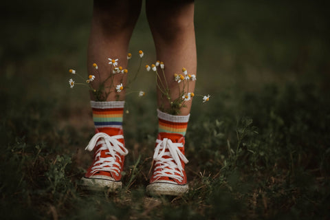 child in field with flowers in their socks