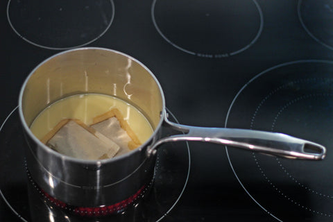 A pot sits on the stove and bring milk, dates, cinnamon sticks, and a tea bag to a boil. 