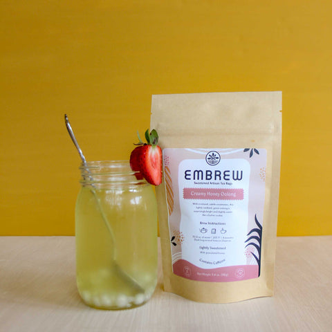 A pouch of Embrew's Creamy Honey Oolong tea and a glass of boba bubble tea.