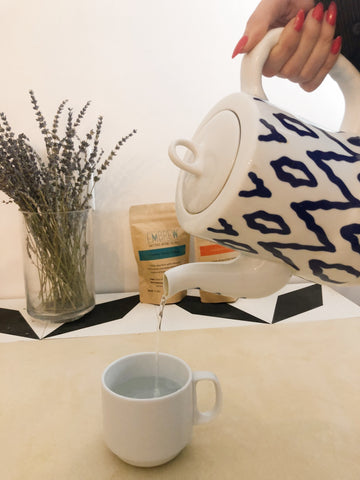 An electric tea kettle pours hot water into a tea cup. 