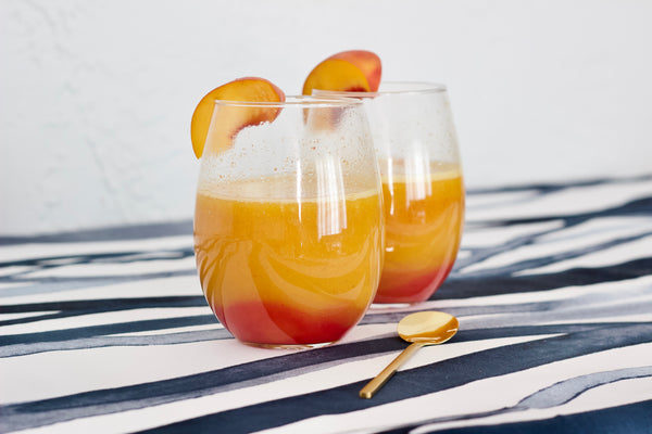 Two Summer Peach Rooibos Sweetened Herbal Tea cocktails on a counter.