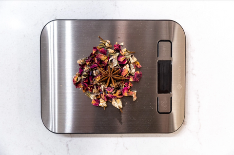 A food scale with a handful of loose tea leaves. 