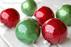 A table full of green and red Christmas tree bulb ornaments. 